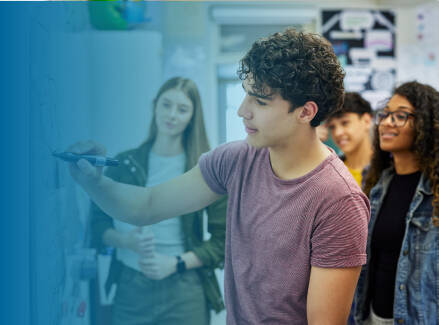 Student writing on a whiteboard with three students watching in the background